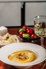 Pumpkin cream soup with croutons, baked chickpeas, sesame, parsley on a brown wooden background. Baked chickpeas with spices. Useful dietary snacks. Served with white wine and cheese