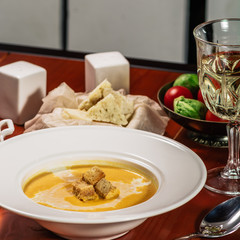 Pumpkin cream soup with croutons, baked chickpeas, sesame, parsley on a brown wooden background. Baked chickpeas with spices. Useful dietary snacks. Served with white wine and cheese