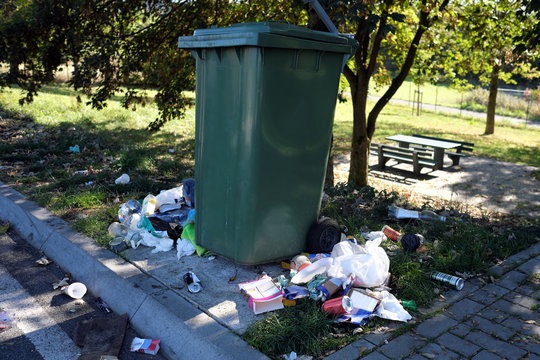 Mülltonne und herumliegender Müll auf Autobahn-Parkplatz - Stockfoto