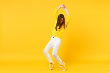 Fototapeta na wymiar Pretty young woman in casual clothes, heart glasses looking down, rising hands, dancing isolated on yellow orange background in studio. People sincere emotions, lifestyle concept. Mock up copy space.
