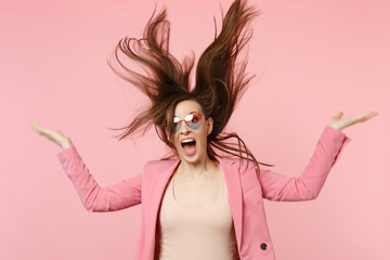 Portrait of crazy screaming young woman in heart glasses jumping with fluttering hair isolated on...