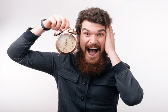 Guy bearded man worry about time left. Time management and discipline. Punctuality and responsibility. Man with clock on white background