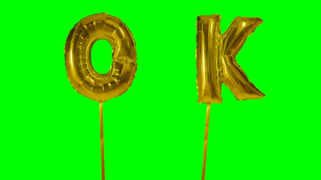 Word ok from helium golden balloon letters floating on green screen