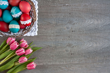 Easter background with pink and white tulips and a basket full of colorful Easter eggs