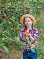 Portrait of a cute girl in a farm garden with a red apple.
