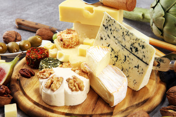 Cheese plate served with figs, various cheese on a platter on wood