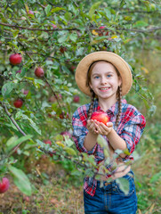 Portrait of a cute girl in a farm garden with a red apple.