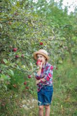 Portrait of a cute girl in a farm garden with a red apple.