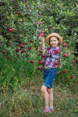 Portrait of a cute girl in a farm garden with a red apple.