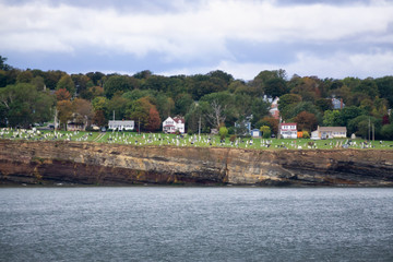 Obraz premium Residential homes on a rocky coast during a cloudy day. Taken in North Sydney, Nova Scotia, Canada.