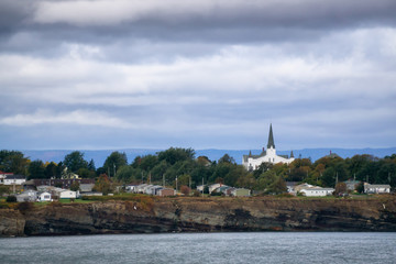 Residential homes on a rocky coast during a cloudy day. Taken in North Sydney, Nova Scotia, Canada.