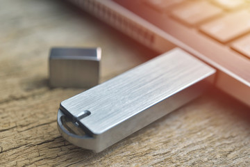 Close up of metal USB flash drive connected to laptop on wood desk