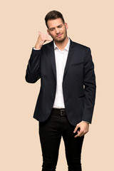 Handsome business man making phone gesture and doubting over ocher background