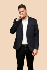 Handsome business man yawning and covering wide open mouth with hand over ocher background