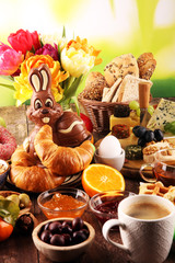 breakfast on table with bread buns, croissants, coffe and eggs