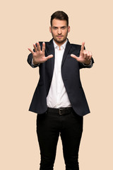 Handsome business man counting seven with fingers over ocher background