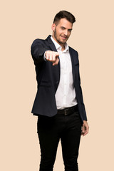 Handsome business man points finger at you with a confident expression over ocher background