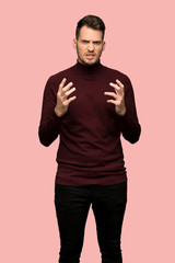 Man with turtleneck sweater frustrated by a bad situation over pink background