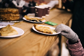 children picks up pancakes on the street. at the festival of Maslenitsa hand out pancakes with condensed milk.