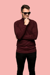 Obraz premium Man with turtleneck sweater with glasses and smiling over pink background