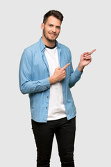 Handsome man pointing finger to the side over grey background