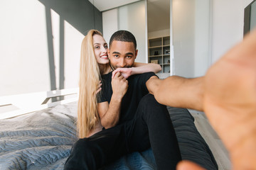 Fototapeta premium Happy sunny morning in modern apartment of joyful couple having fun together. Making selfie, expressing true positive emotions, kissing hand, love, leisure, cheerful mood, smiling, joy