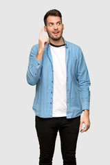 Fototapeta premium Handsome man intending to realizes the solution while lifting a finger up over grey background