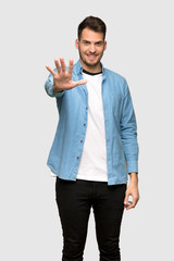 Handsome man counting five with fingers over grey background