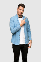 Handsome man surprised and pointing side over grey background