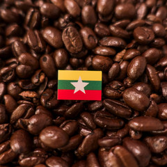 a Myanmar flag placed over roasted coffee beans