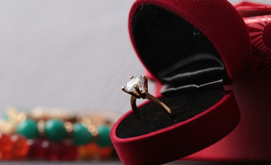 White gold diamond ring on top of colored stones. Romantic background ( Valentine's Day) 