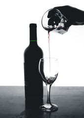 wine bottle in white background and hand dropping the wine