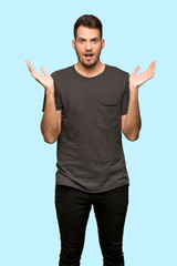 Man with black shirt with shocked facial expression over blue background