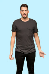 Man with black shirt with surprise facial expression over blue background