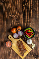 raw steak bifé on wooden board and spices on wood