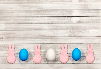 White wooden easter background with pink bunnies, white and blue easter eggs