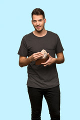 Man with black shirt holding a wallet over blue background