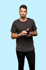Man with black shirt holding a wallet over blue background