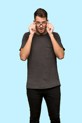 Man with black shirt with glasses and surprised over blue background