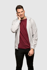 Man with sweatshirt having doubts over grey background