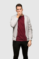 Man with sweatshirt covering mouth with hands for saying something inappropriate over grey background