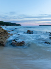 Water motion at the beach shore around the rocks.
