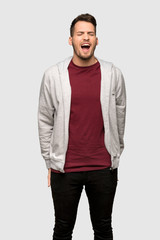 Fototapeta premium Man with sweatshirt shouting to the front with mouth wide open over grey background