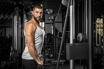 Fototapeta na wymiar Bodybuilding. Bearded man standing doingcable straight arm pulldown at gym looking camera confident