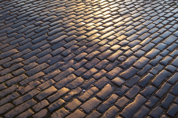 Fototapeta premium Close up view of wet, dark and sunlit cobble paved street, Edinburgh