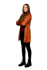 Full-length shot of Young woman with coat with arms crossed and looking forward on isolated white background