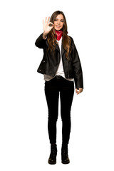 Fototapeta premium Full-length shot of Young woman with leather jacket showing an ok sign with fingers on isolated white background