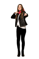 Full-length shot of Young woman with leather jacket points finger at you while smiling on isolated white background