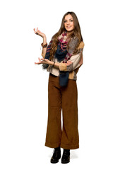 Full-length shot of Young hippie woman extending hands to the side for inviting to come on isolated white background