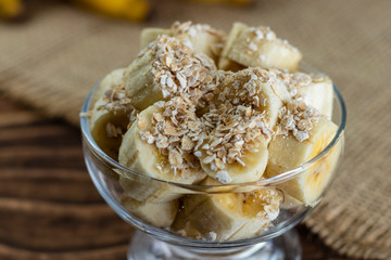 close up on glass jar with pieces of banana with oats, Wooden and jute Background